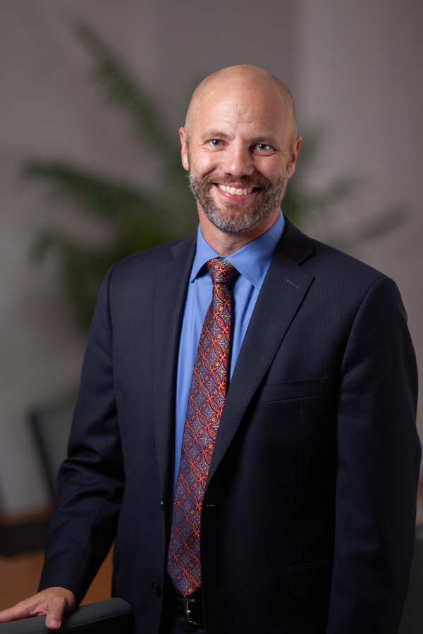 Todd Nicolet, a bald white man with a salt and pepper beard wearing a business suit.