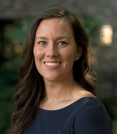 A smiling woman with light skin and long brown hair