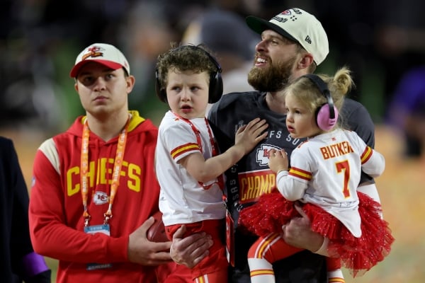 A picture of Harrison Butker holding his two young children after the Chiefs beat the Eagles in the 2023 Super Bowl.