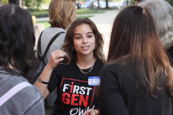 A student wearing a first-gen OWU shirt speaks with two other students.