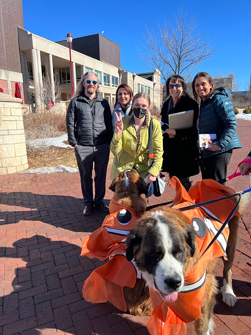 Students pose with dogs in goldfish costumes at the University of Denver.