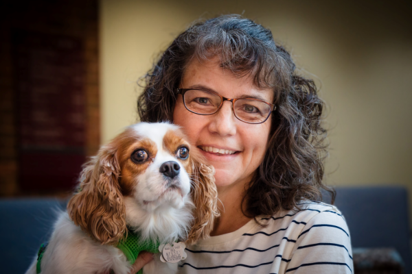 Margaret Bultas holds her spaniel, Jessie, for a photo, smiling.