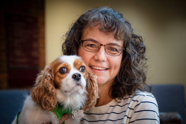 Margaret Bultas holds her spaniel, Jessie, for a photo, smiling. 