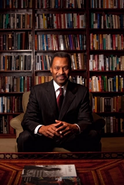 John Silvanus Wilson Jr., author of Hope & Healing, sits in front of a tall bookshelf. 