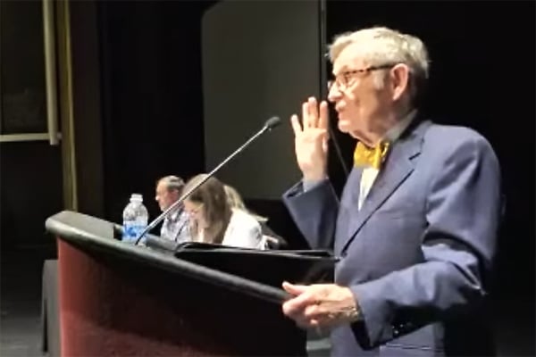 Gordon Gee, a light-skinned older man with light hair wearing a yellow bow tie, speaks at a lectern. 