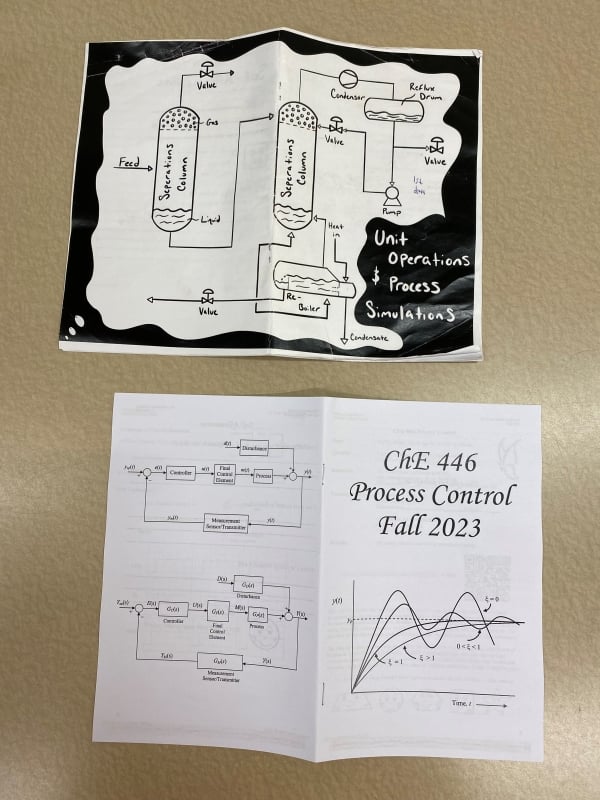 Two syllabus magazine lie on a beige table, one for unit operations and process solutions at the University of Connecticut and the other for Process Control at the University of Massachusetts, Amherst