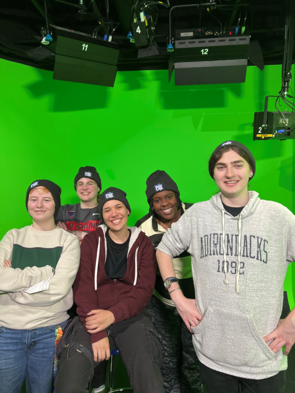 DIGI student workers and lab head Jes Klass pose for a photo in front of a greenscreen background.