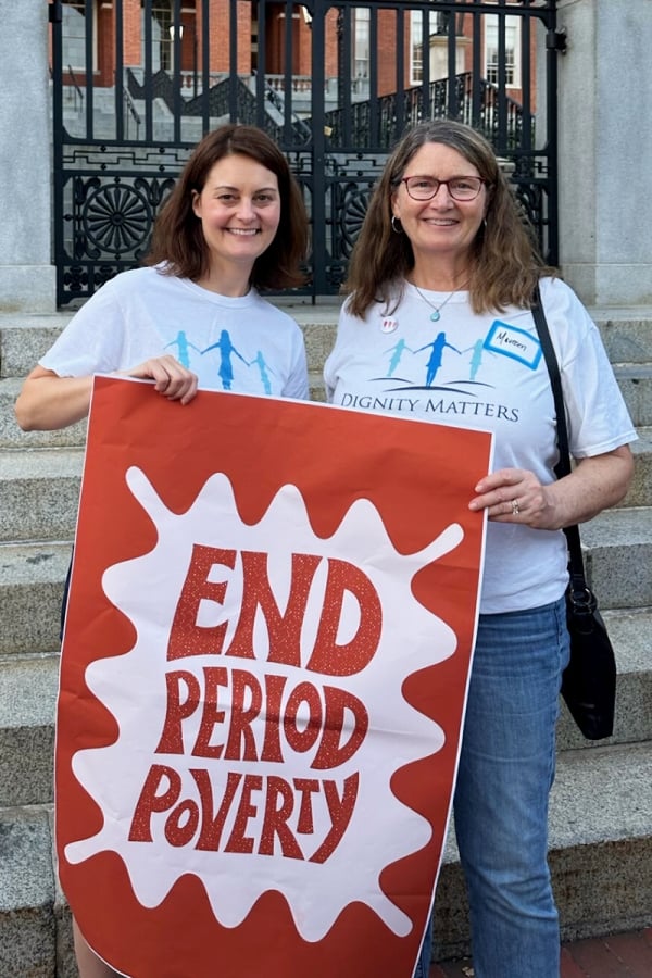Women hold sign that says "end period poverty"
