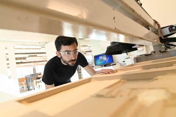 A student works on a computer numerical control machine in a shop.