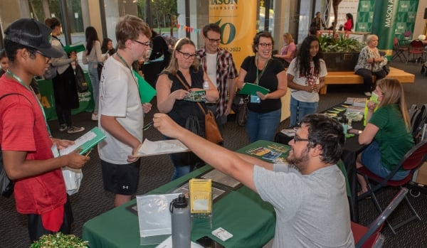 Students mill about a campus hall in front of activity tables