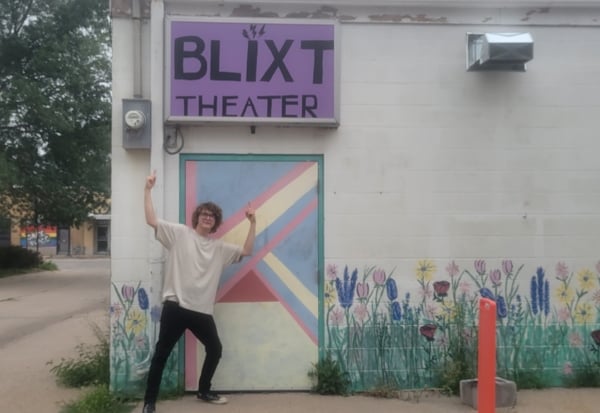 A student poses in front of the entrance to BLIXT ARTS LAB in Nebraska. 