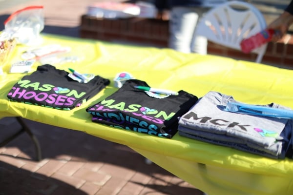 Three stacks of Mason Chooses Kindness T-shirts lie on a table