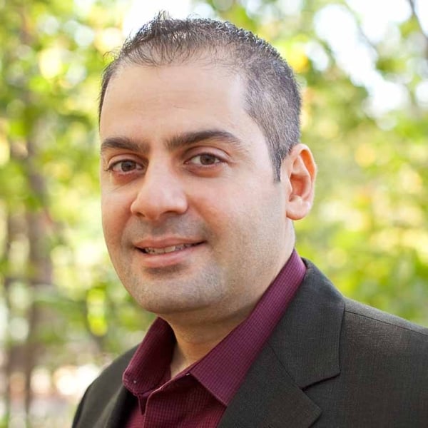 Headshot of middle-aged man with light brown skin and dark hair, wearing a black jacket over a plum-colored collared shirt