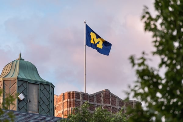 A flag with an M flies above a brick building