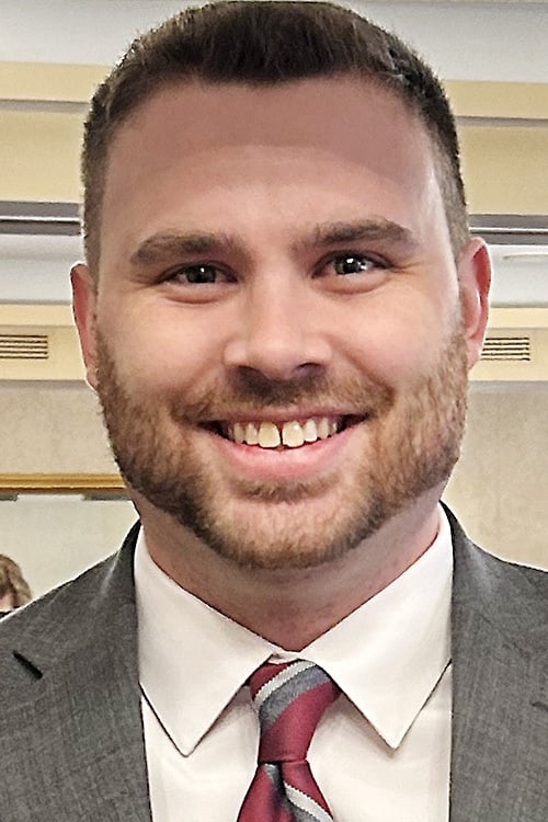 Headshot of Gavin Stephens, a light-skinned man with short hair and a short beard, wearing a suit and tie