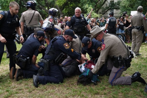 A person is detained by police on the campus of the University of Texas in Austin