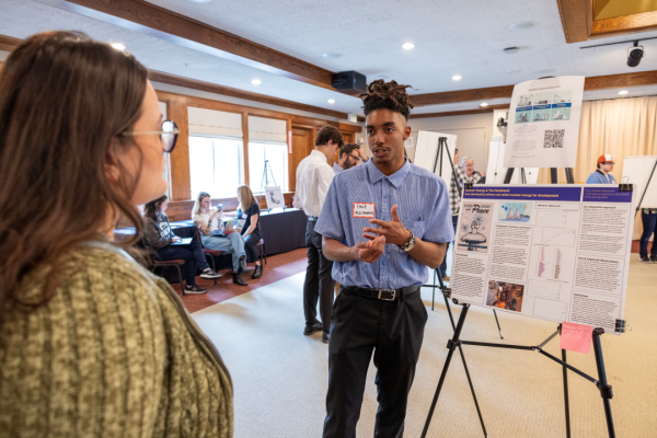 A student discusses his research poster with a faculty member