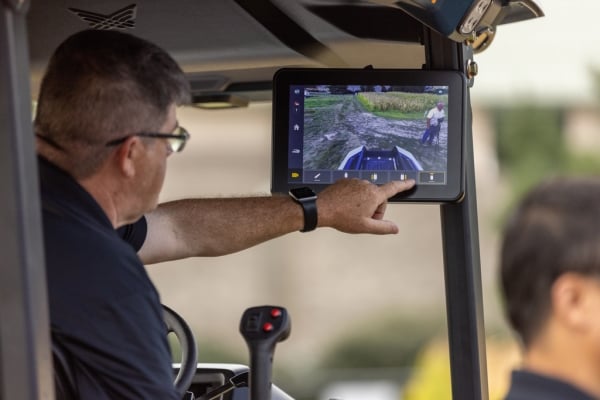 A man points toward a screen while sitting in a tractor