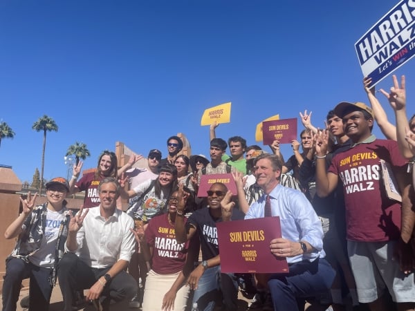 ASU students in Sun Devils for Harris Walz T-shirts pose with signs and several politicians.