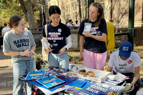 Students stand around a table wearing shirts supporting Kamala Harris