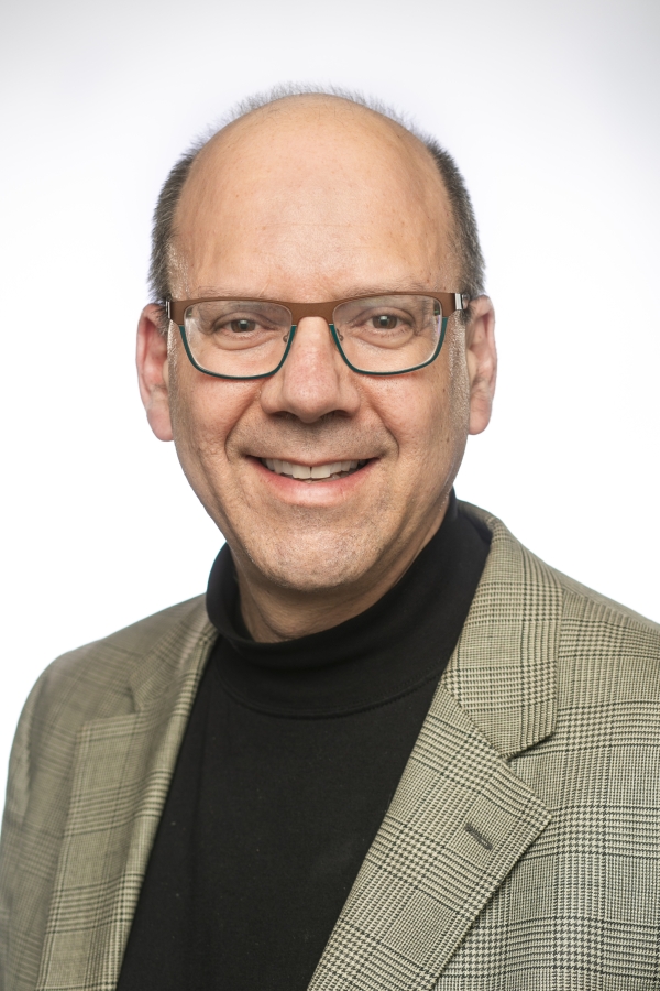 Ed Balleisen, a light-skinned man wearing glasses and a checked suit jacket over a black mock turtleneck