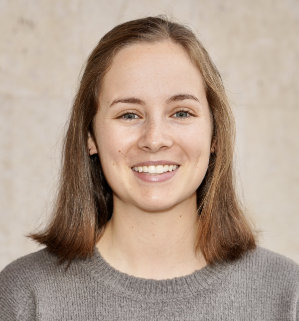 A photo of a woman with a shoulder-length haircut on a plain brown background.