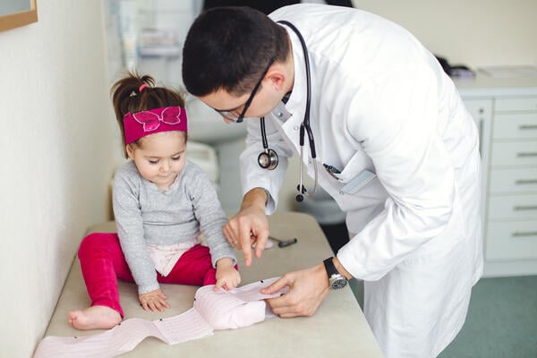 A photo of a toddler girl and her physician, who is holding EKG results.