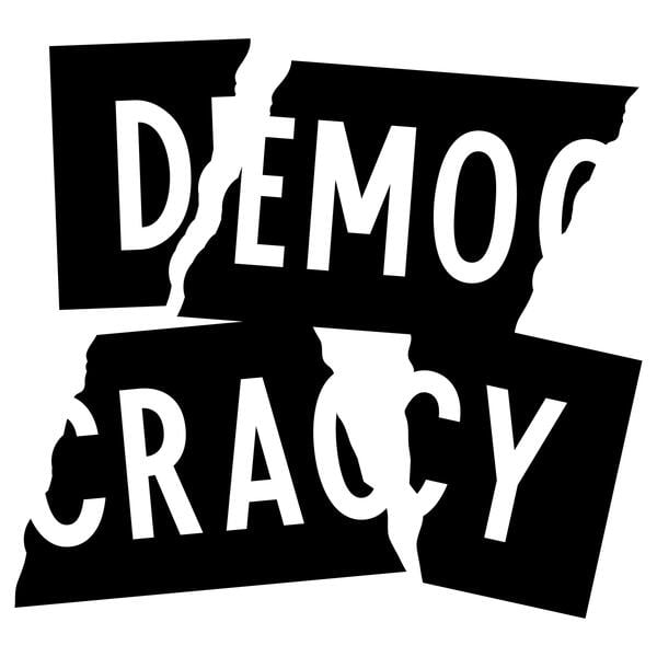 A black and white sign with the word "Democracy," broken apart.
