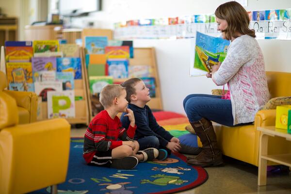 A woman reads a picture book to two children.