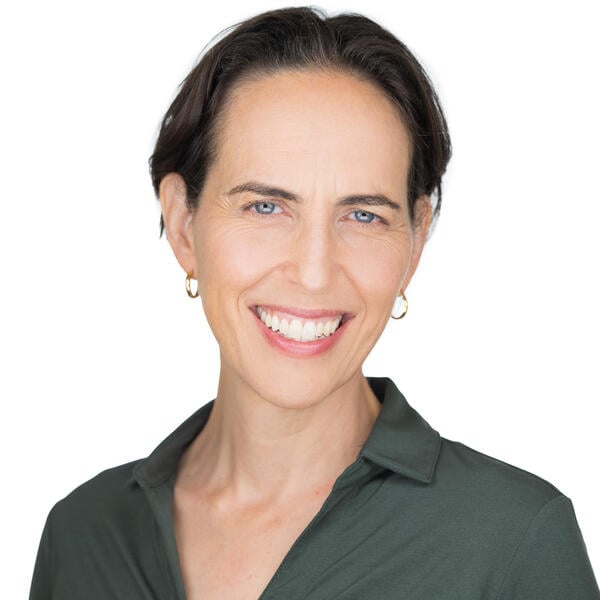 Sarah Federman smiles for a headshot in a gray collared shirt