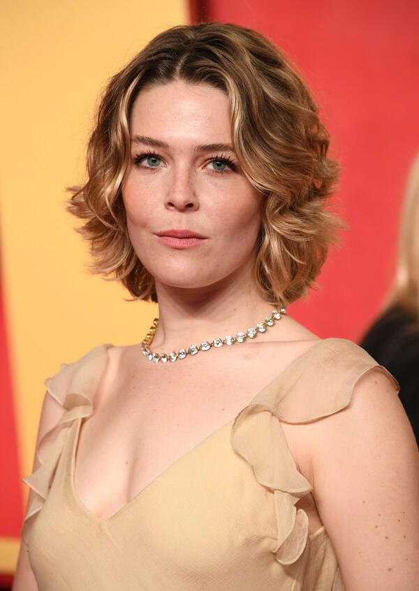 Maggie Rogers, a white woman with blond hair in a layered bob, wears a skin-tone dress with ruffled sleeves and a necklace.