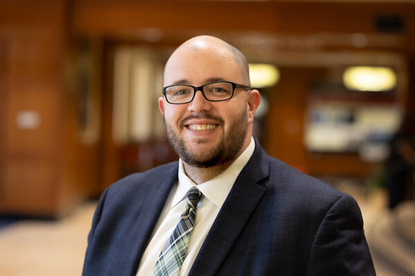 Adam Landreth, a bald white man with glasses and a beard wearing a suit.