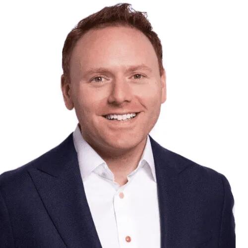 Andrew Hermalyn, a light-skinned, clean-shaven man wearing a blazer over a white button-down shirt with the collar open.