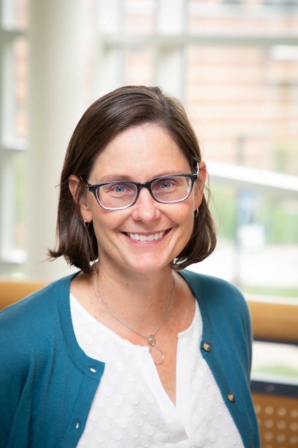 Joan Remski, a light-skinned soman with a brown bob and glasses wearing a blue cardigan over a white blouse.
