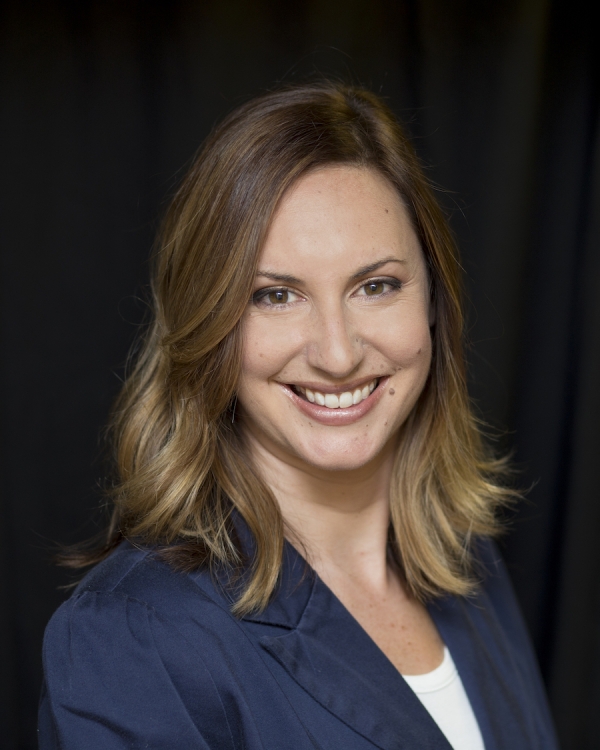 A light-skinned woman with light brown shoulder-length hair wearing a blue blazer.