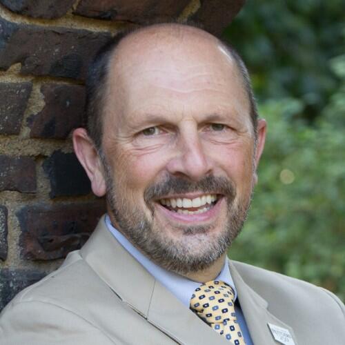 Richard Novak, a white man with a beard, wearing a tan suit.
