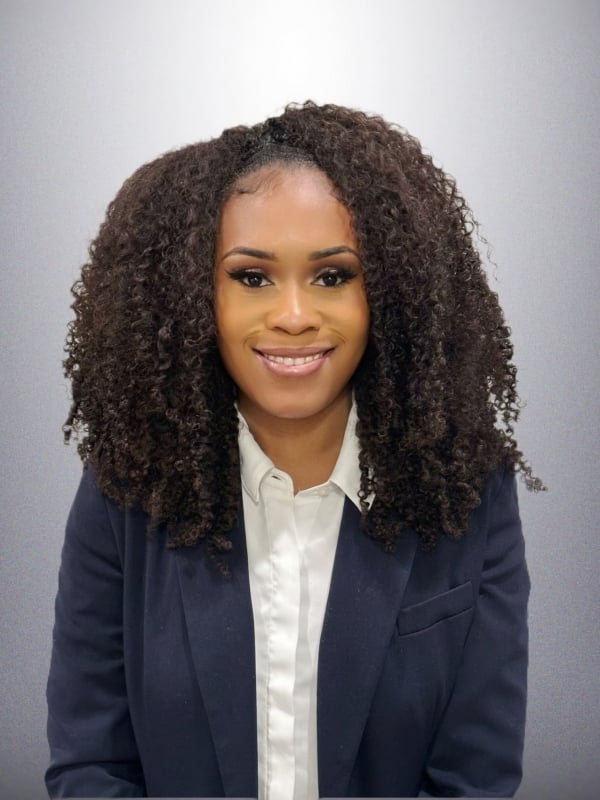 Brittany Washington, a woman with light brown skin and curly dark hair, wearing a blue blazer over a white button-down shirt.