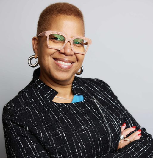 Headshot of Ronné Turner, a Black woman with short hair wearing statement glasses, large earrings and a black and white jacket.