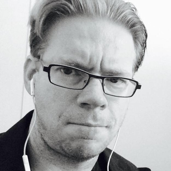 A photo of Michael Patrick Rutter, wearing glasses and wired white headphones.