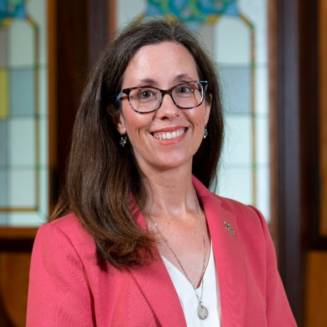 April Belback, a  woman with long dark hair who is wearing glasses