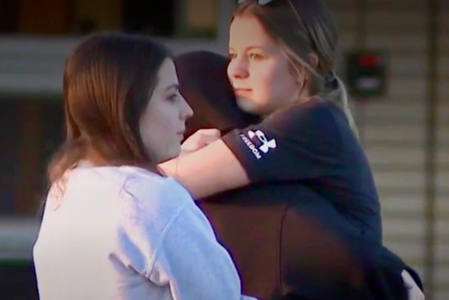 A female student comforts another with a hug