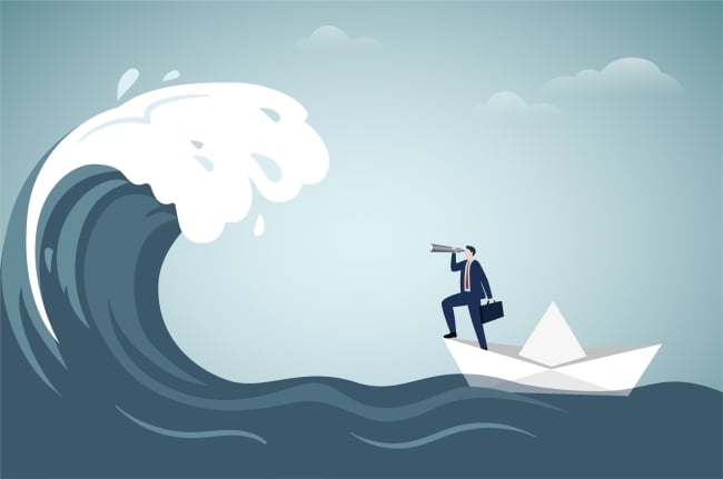 A businessperson in a paper boat uses a telescope to look at an oncoming wave.