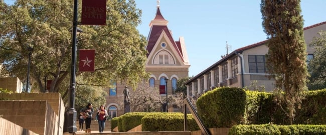 Two students walk through a college campus outside during the day