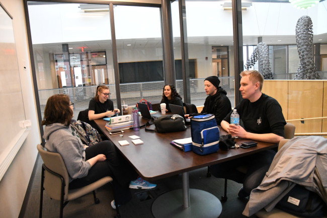 A group of Youngstown State University students sit at a table, smiling.