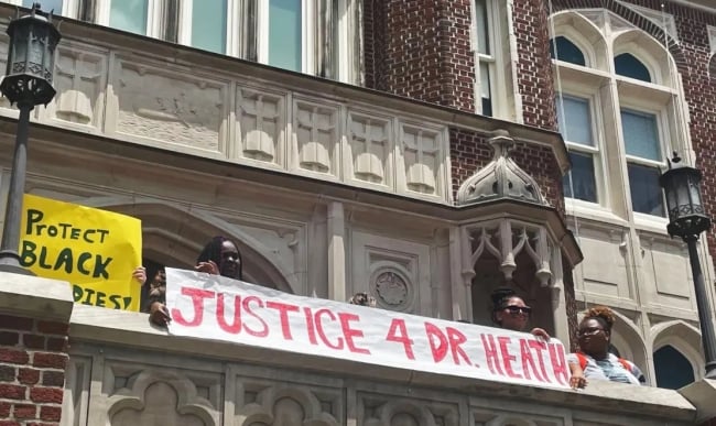 Students hold a banner that says "Justice 4 Dr. Heath" at a protest to save Scott Heath's job at Loyola University New Orleans.