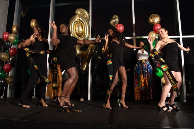 Four Black women dance on stage at Illinois State University's Umoja, a celebration of Black graduates.