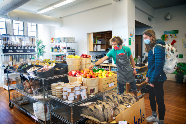 A student employee assists their peer in shopping for fruit at Anabel's Grocery