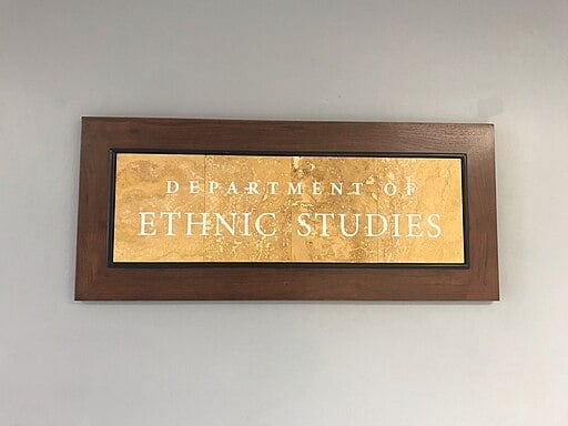 A gold plaque on a wooden background reads "Department of Ethnic Studies."