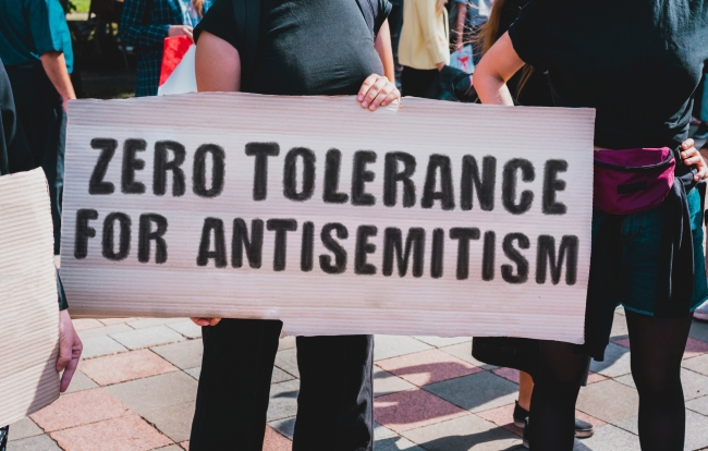 A person holds a sign saying "Zero tolerance for antisemitism"