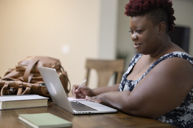 A female student in her 40s works on a laptop.